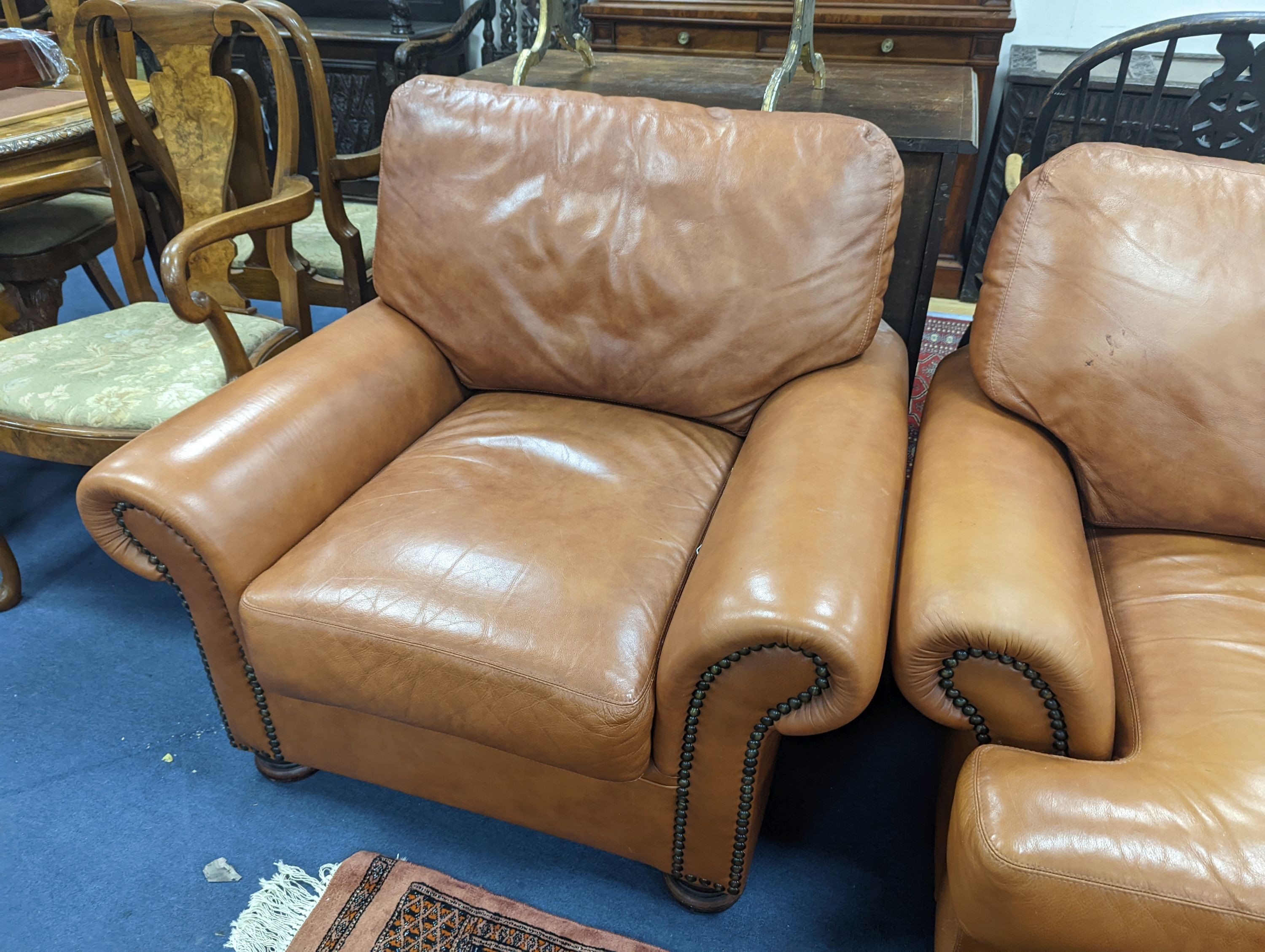A contemporary tan leather three piece suite and footstool, settee length 150cm, depth 90cm, height 84cm